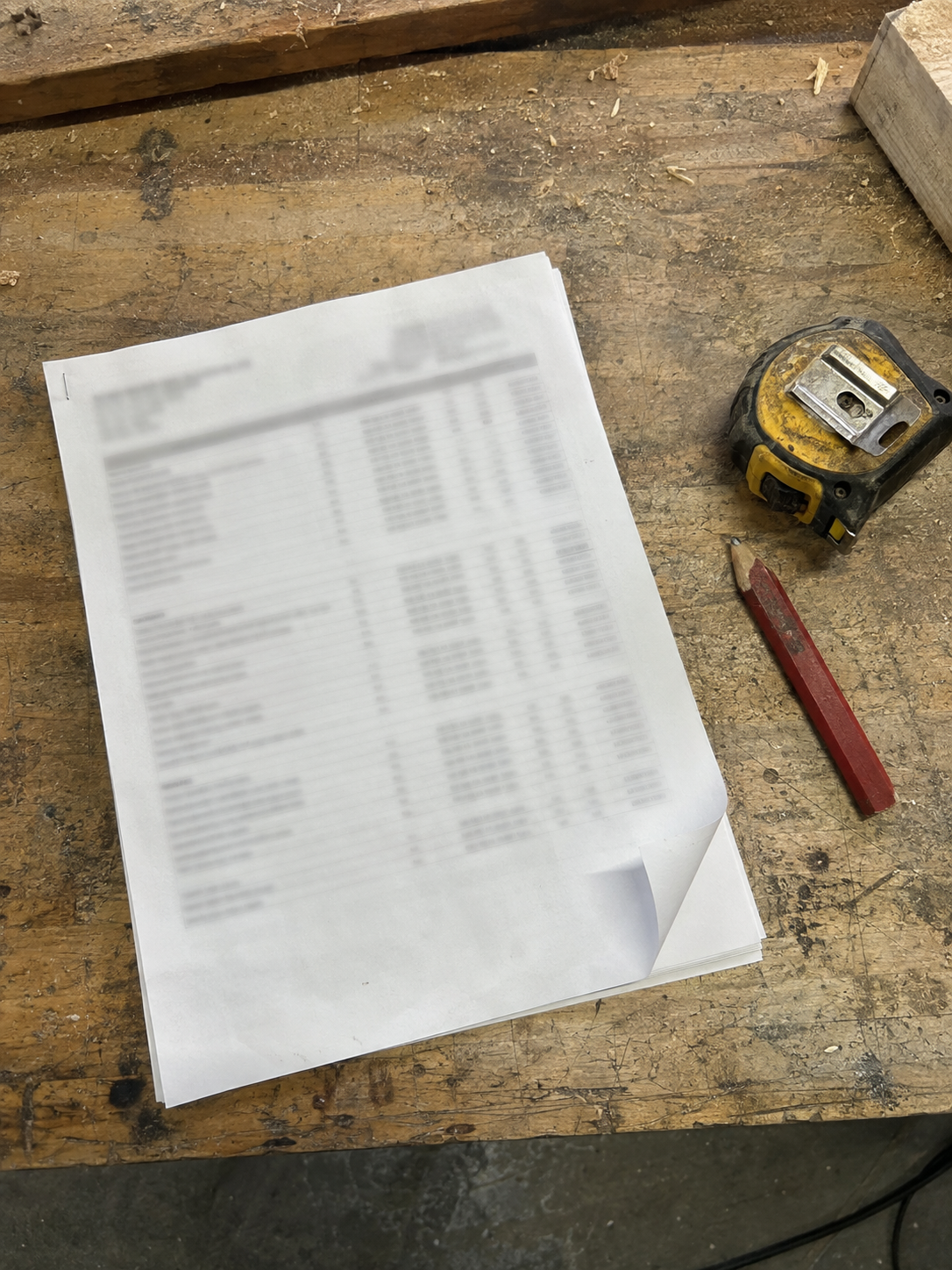 Printed job margin report on a workbench next to a tape measure and a pencil